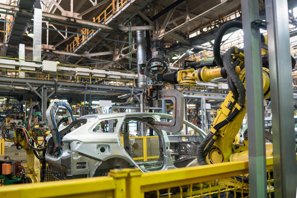 Car bodies getting assembled by robots on a large assembly line.