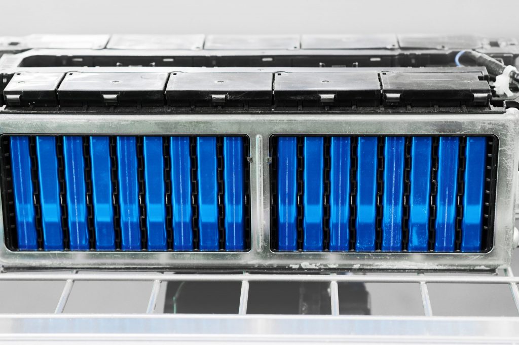Stacks of electric vehicle batteries in their battery tray that are being secured. 