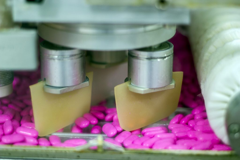 Machine sorting pink pills into their packaging. 
